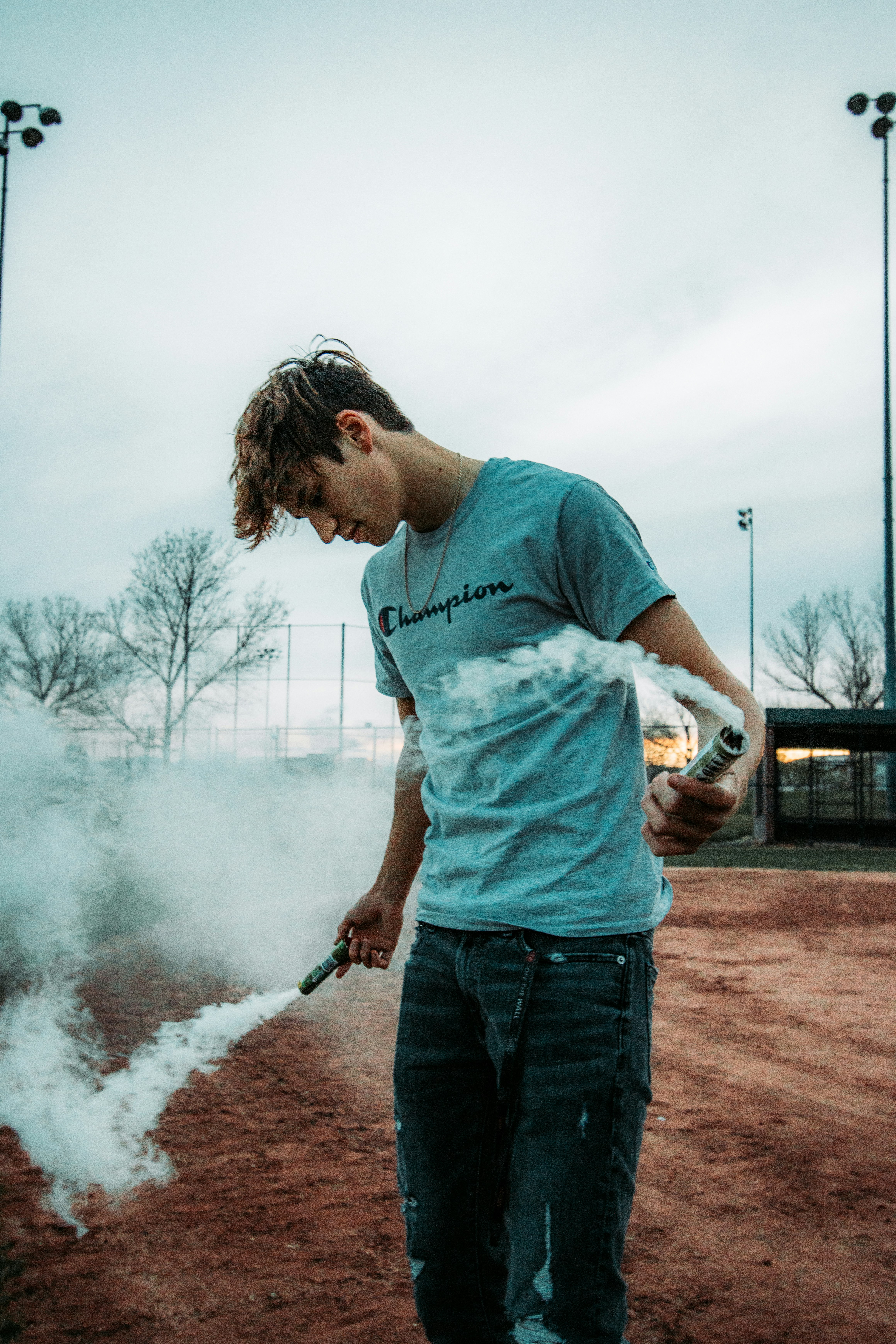 man in blue crew neck t-shirt and blue denim jeans holding smoking pipe